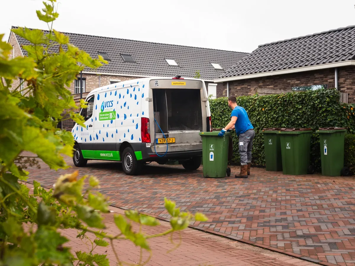 Bus van VCCS in een straat met afvalcontainers
