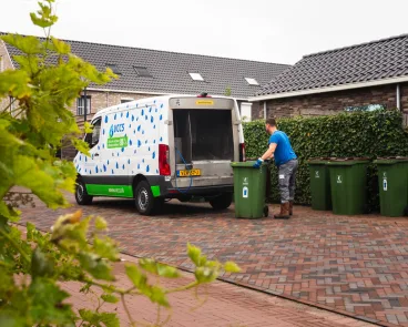 Bus van VCCS in een straat met afvalcontainers